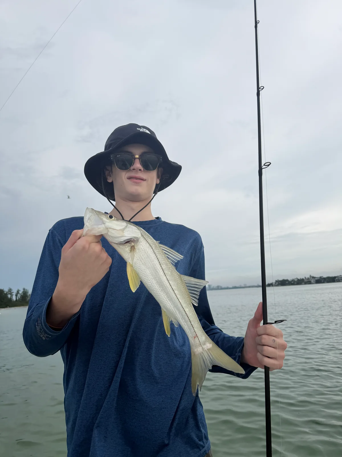 Angler holds a snook beside a fishing rod on the water — October 9, 2026.